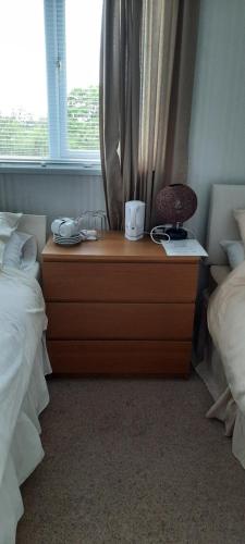 a bedroom with a dresser with a lamp and a window at The White Heather Hotel in Wigton
