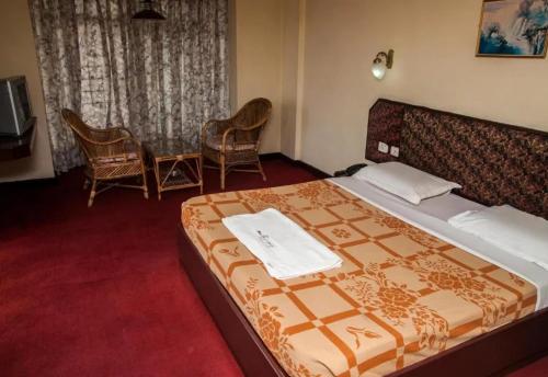 a bedroom with a large bed and two chairs at Edassery Cokkers tower in Kodaikānāl