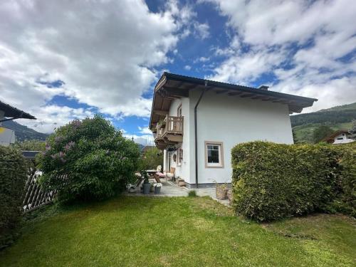 a small white house with a green yard at Chalet Bergglück in Piesendorf