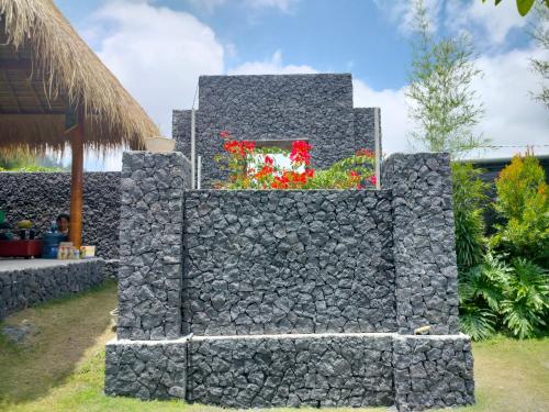 a stone wall with a window and flowers at Lake Batur Cottage 3 in Kubupenlokan