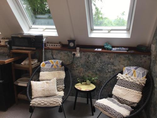 a room with two chairs and a table and two windows at The Granary Country Retreat in Lampeter