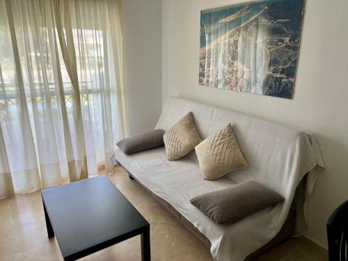 uma sala de estar com um sofá branco e uma mesa em Apartamento Pinares del Portil a pie de playa em El Portil