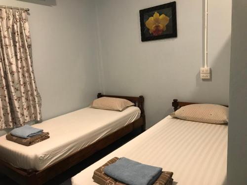 two twin beds in a room with a window at Vitoonguesthouse2fanrooms & Aircondition in Sukhothai