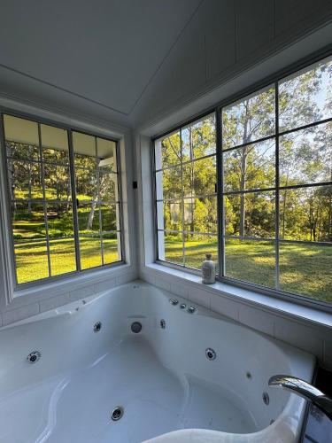 a bath tub in a bathroom with windows at Hinterland Heights in Canungra