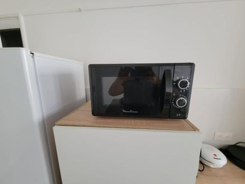 a person taking a picture of a microwave on a refrigerator at Chambres spacieuses hyper centre in Saint-Étienne