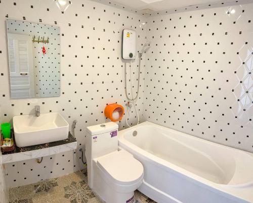 a bathroom with a white tub and a toilet and a sink at Mean Mean Bungalow in Phumĭ Véal Sbov
