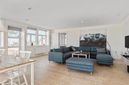 a living room with a blue couch and a table at Feriehus med havudsigt in Hasle