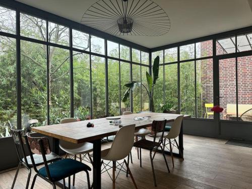 - une table et des chaises dans une pièce dotée de grandes fenêtres dans l'établissement Charming family home to rent for holidays & only 10 mins to Paris, à Colombes