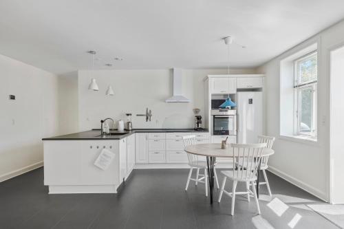a kitchen with white cabinets and a table and chairs at Feriehus med havudsigt in Hasle