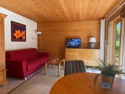 un salon avec un canapé rouge et une table dans l'établissement La Joly - ChaletYap, à La Chapelle-dʼAbondance