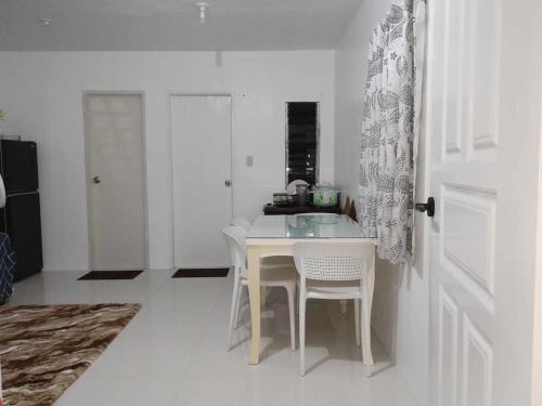 a white kitchen with a table and chairs at tadzmahal home in Pagadian
