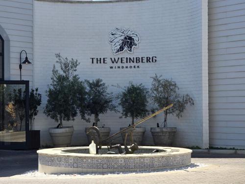 a sign on a building with a fountain with trees at Am Weinberg Estate - The Presidential Villa - A Sanctuary of Luxury and Elegance in Windhoek