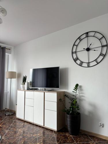 een woonkamer met een tv en een klok aan de muur bij Kilińskiego 35 in Ełk