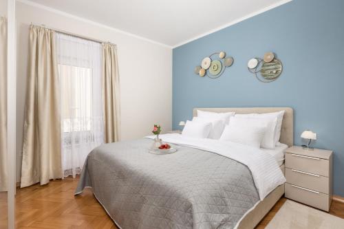een slaapkamer met een groot bed met blauwe muren bij Apartment Marina -1st row to the sea in Opatija