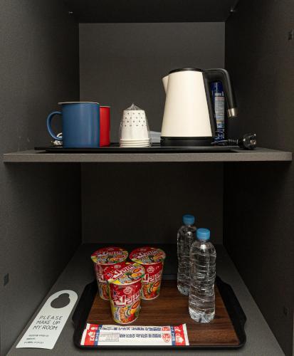 a shelf with cups and water bottles on a tray at Hotel The Grang Jungmun in Seogwipo
