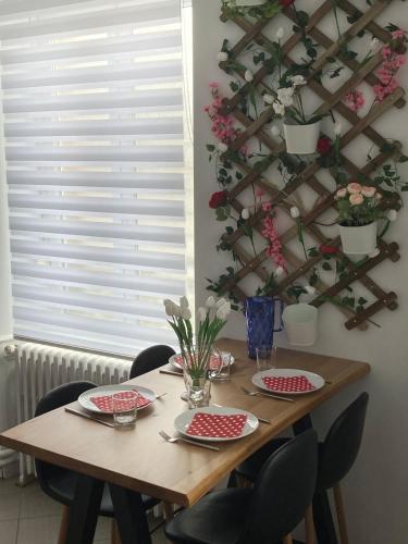 une table en bois avec des chaises, des assiettes et des fleurs. dans l'établissement Black & White Harmony, à Belfort