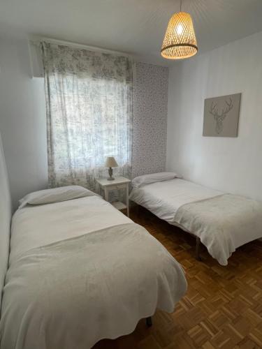 a bedroom with two beds and a lamp and a window at Apartamento en Getxo. Cercano al puerto viejo in Getxo