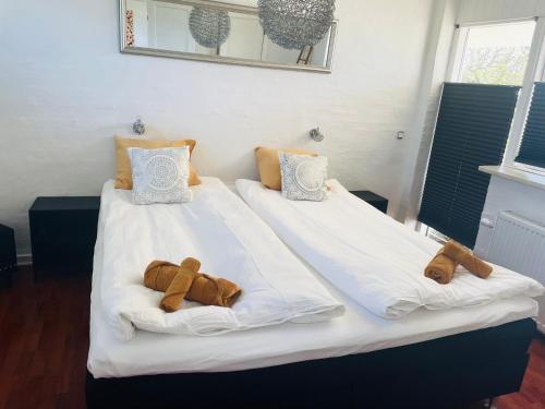 Duas camas com lençóis brancos e toalhas castanhas em Lejlighed Edelweiss em Svendborg