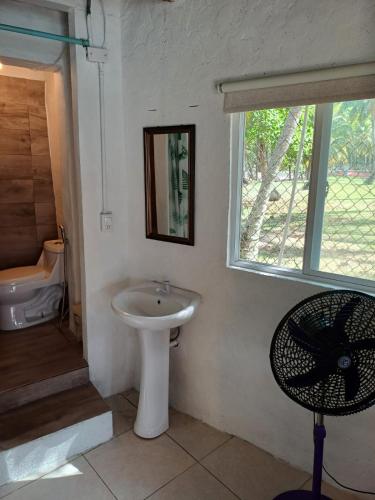 a bathroom with a sink and a window and a chair at Cabaña La Punta in Isla Grande