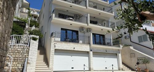 un edificio blanco con dos puertas de garaje y escaleras en Villa Dian, en Neum