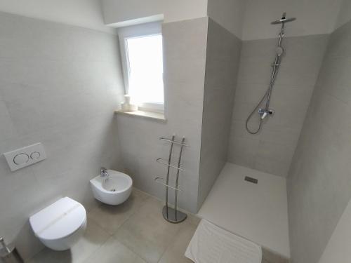 a white bathroom with a toilet and a shower at Villa Badi in Umag