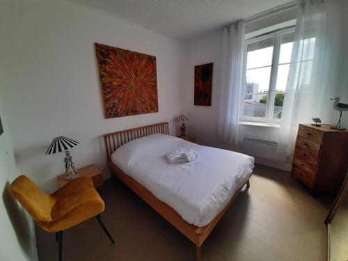um quarto com uma cama, uma cadeira e uma janela em Les 3 Cheminées em Granville