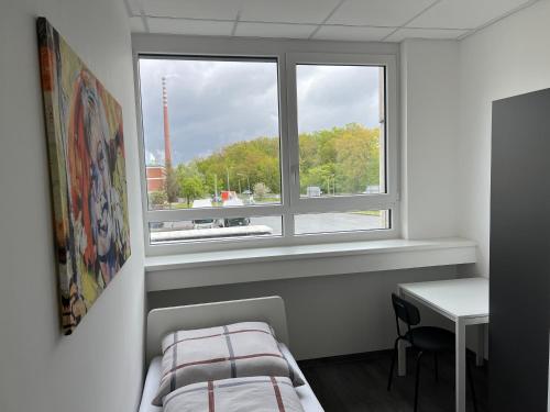 a bedroom with a window and a bed and a desk at DRIVER ROOMS in Nürnberg