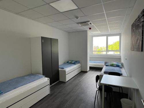 a room with two beds and a desk and a window at DRIVER ROOMS in Nuremberg