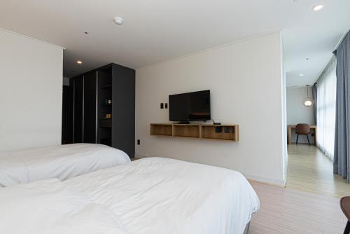 a bedroom with two beds and a tv on the wall at Hotel The Grang Jungmun in Seogwipo