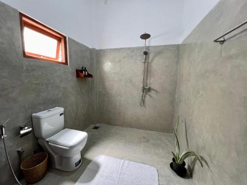 a bathroom with a toilet and a window at Triton Dondra in Dondra West