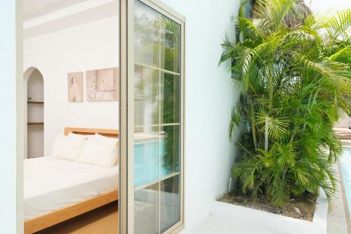 邦勞的住宿－奧那海明珠度假村，一间设有滑动玻璃门的客房,配有棕榈树