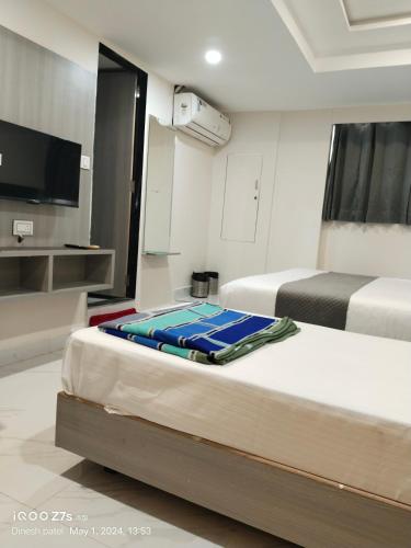 アーメダバードにあるHotel SSのベッド2台、薄型テレビが備わるホテルルームです。