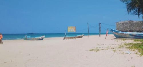 a beach with two boats sitting on the sand at Beach Walk Villa in Trincomalee