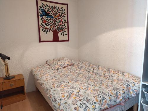 - une chambre dotée d'un lit avec une photo d'arbre sur le mur dans l'établissement T2 proche ligne 14 Kremlin Bicêtre, au Kremlin-Bicêtre