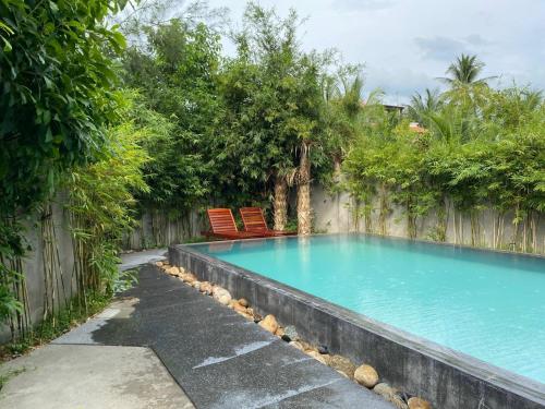 a swimming pool with two chairs and a fence at Palm View Villa in Hoi An