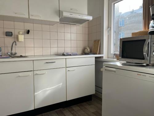 a kitchen with white cabinets and a flat screen tv at Hotel Noordzee in Zandvoort