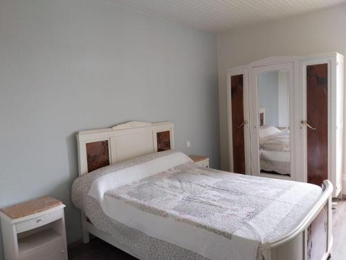 une chambre blanche avec un lit et un miroir dans l'établissement maison de campagne en pierre, à Dégagnac