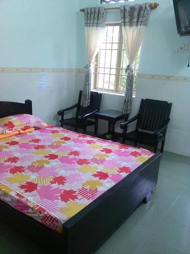 - une chambre avec un lit, deux chaises et une fenêtre dans l'établissement Nhà nghỉ Mỹ Hà, à Thôn Khánh Cam