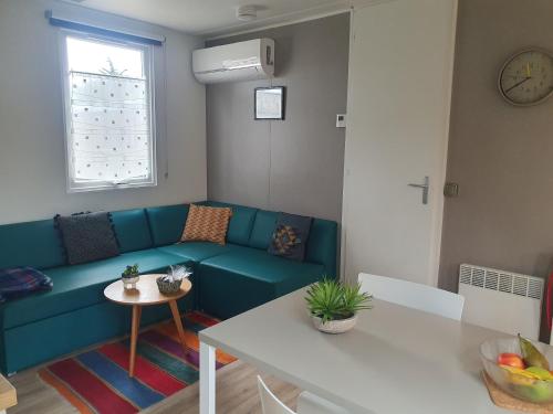 ein Wohnzimmer mit einem blauen Sofa und einem Tisch in der Unterkunft Mobilhome Grand confort 6 à 8 personnes in Sainte-Marie-de-Ré