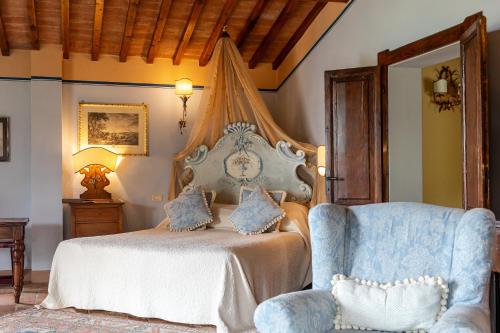a bedroom with a bed and a blue chair at Il Falconiere Relais & Spa in Cortona