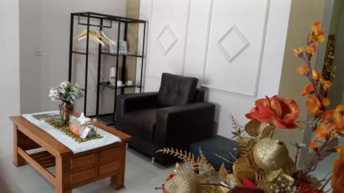 a living room with a black chair and a coffee table at Rezka Roomz Syari'ah in Ende
