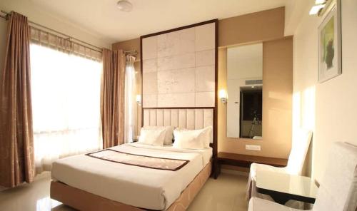 Hotel Executive Silver Inn في أورانغاباد: غرفة نوم بسرير ونافذة وكرسي