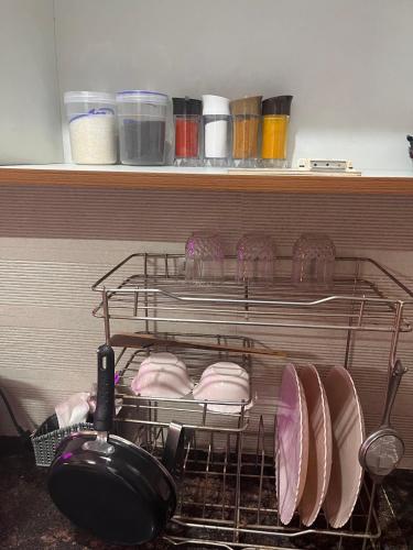 a drying rack with plates and pans on a shelf at Bella Dreamy near expo mart greater Noida in Greater Noida