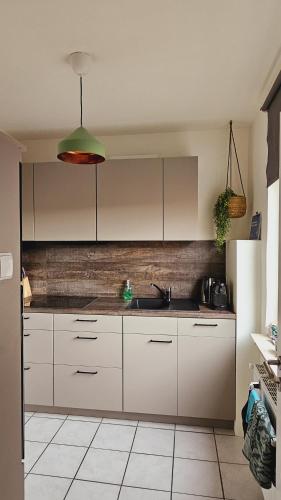 a kitchen with white cabinets and a green pendant light at Ferienwohnungen Bentheimer Altstadt in Bad Bentheim