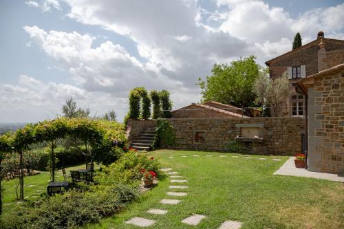 a garden in front of a brick building with a yard at Il Falconiere Relais & Spa in Cortona