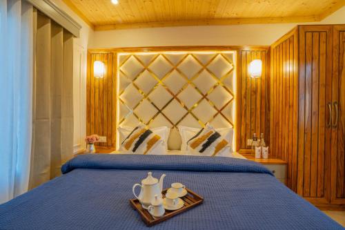 a bedroom with a blue bed with a tray of teaisers at PerfectStayz Value Paradise near Bhatta Falls in Mussoorie