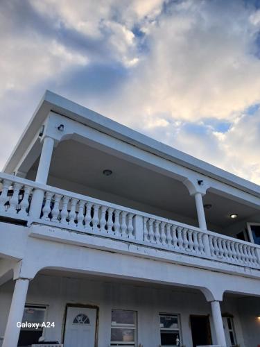 a white house with a balcony and a cloudy sky at New condo with sea view 1 in Wheeland Settlement