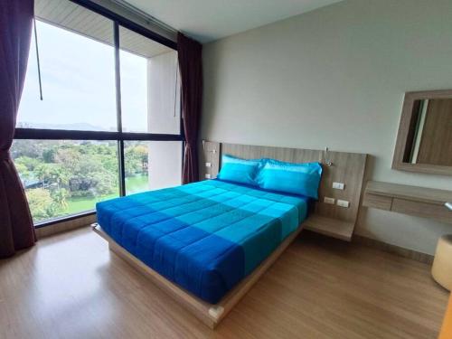 a bedroom with a blue bed with a large window at Condo 1 bed in Phuket City Center 8th Floor in Ban Rangeng