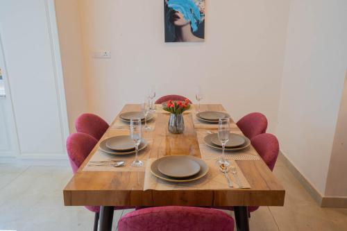 a wooden table with red chairs and plates and wine glasses at PerfectStayz Value Paradise near Bhatta Falls in Mussoorie