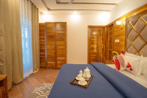 a bedroom with a bed with a blue comforter and a table at PerfectStayz Value Paradise near Bhatta Falls in Mussoorie